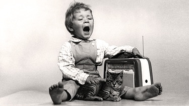 Kleinkind mit Katze singt zu Radiomusik, 60er Jahre | Bild: picture alliance / Presse-Bild-Poss | Oscar Poss